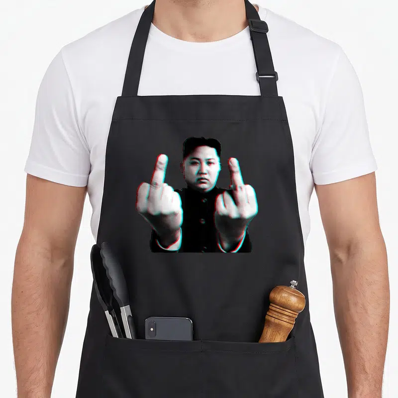 Tablier de cuisine noir avec une illustration de Kim Jong Un levant les deux en style glitch.