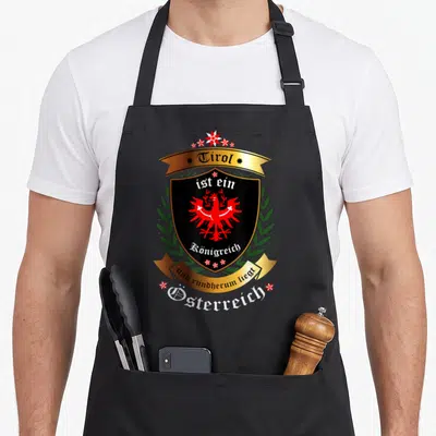 Tablier de cuisine noir avec armoiriesrol aigle rouge couronne laurier et texte allemand en lettres blanches et dorées.