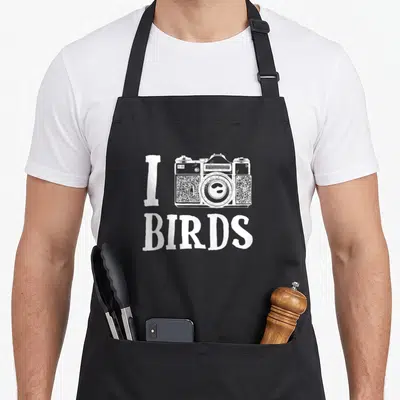 Tablier de cuisine noir avec inscription I BIRDS et dessin d'appareil photo blanc au centre.