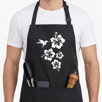 Tablier de cuisine noir avec silhouette blanche de colibri et quatre fleurs d'hibiscus stylisées disposées en cascade.
