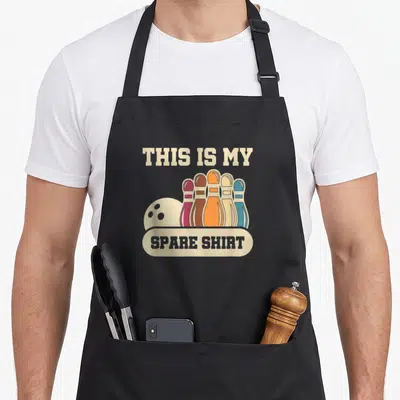 Tablier de cuisine noir avec illustration de quilles de bowling multicolores et texte humoristique en anglais.