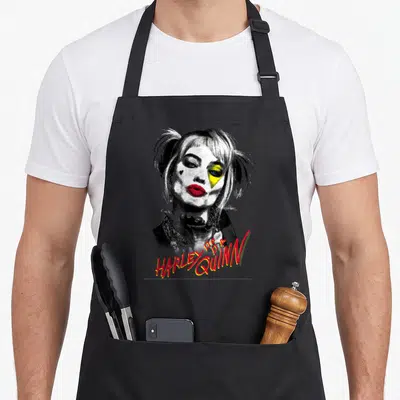 Tablier de cuisine noir avec portrait graphique Harley Quinn aux cheveux pigtails et texte rouge Harley pour Quinn