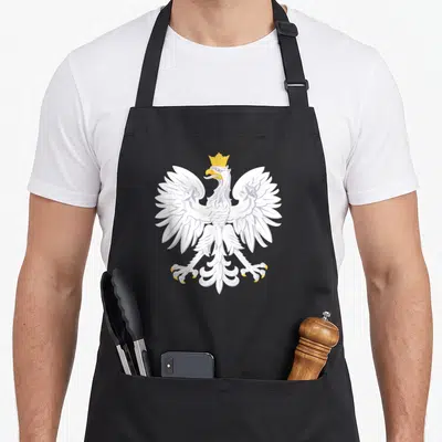 Tablier de cuisine noir avec un aigle polonais blanc couronné aux ailes déployées et bec jaune.