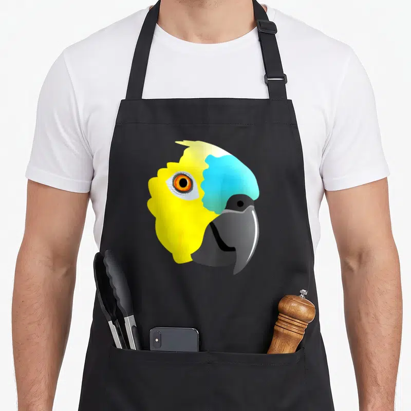 Tablier de cuisine noir avec tête de perroquet amazonien au front bleu et plumage jaune vif, œil orange et bec gris foncé.