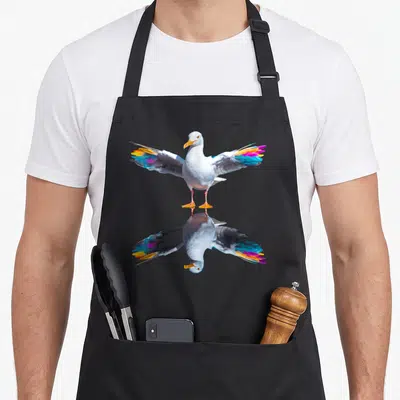 Tablier de cuisine noir avec une mouette aux ailes colorées et son reflet symétrique imprimé au centre.