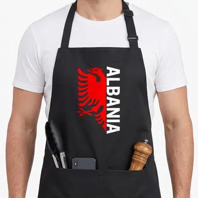 Tablier de cuisine noir avec aigle rouge stylisé et inscription verticale ALBANIA en blanc.