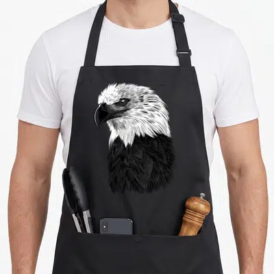 Tablier de cuisine noir avec illustration gravure d'une tête d'aigle aux traits fins et au regard intense.