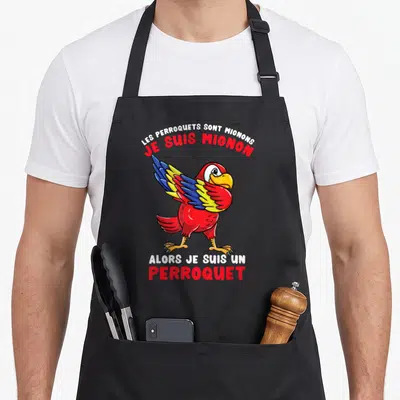 Tablier de cuisine noir avec illustration d'un perroquet rouge aux ailes bleues et jaunes, entouré de texte humoristique en rouge et blanc.