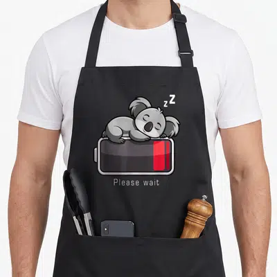 Tablier de cuisine noir avec un koala gris dormant sur une icône de batterie rouge et le texte Please wait en blanc.