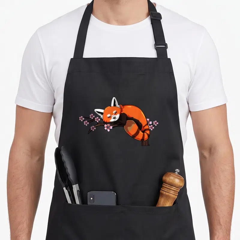 Tablier de cuisine noir avec illustration d'un renard roux dormant sur une branche de fleurs de cerisier roses.