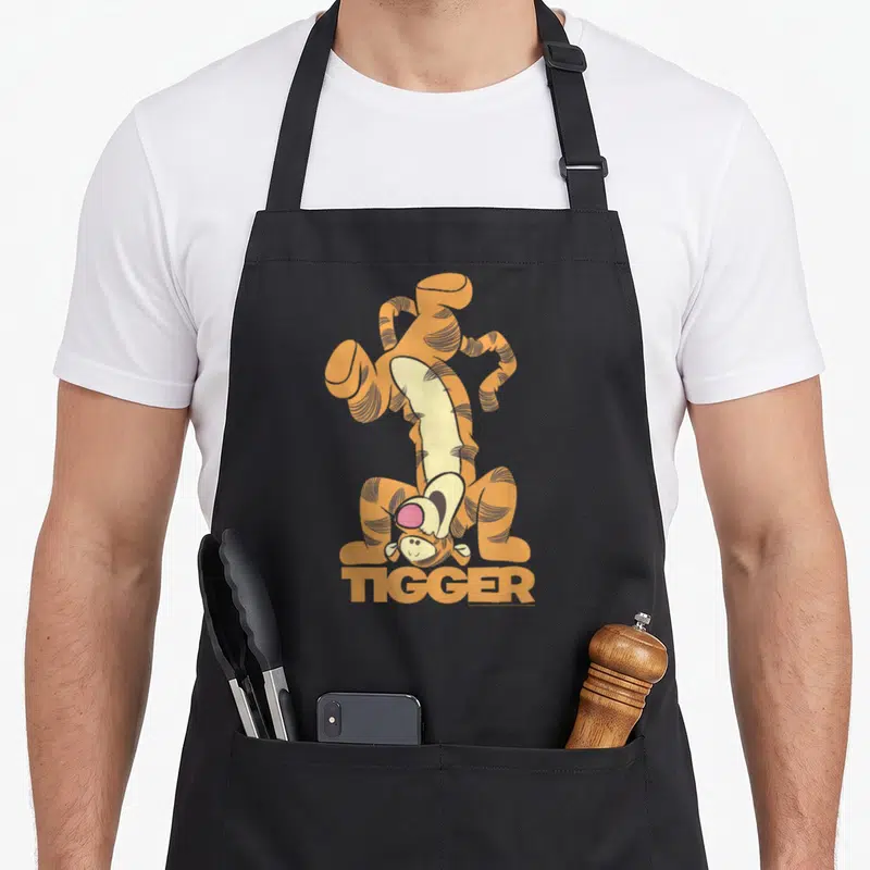 Tablier de cuisine noir avec Tigger le tigre orange effectuant un saut acrobatique au-dessus du mot TIGGER.