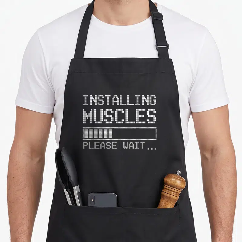 Tablier de cuisine noir avec texte blanc pixelisé Installing Muscles et barre de chargement graphique.
