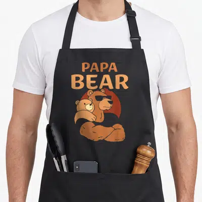 Tablier de cuisine noir avec inscription Papa Bear et illustration d'un ours musclé tenant un ourson dans ses bras.