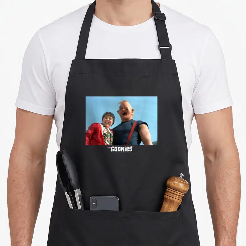 Tablier de cuisine noir avec une illustration de Chunk et Sloth des Goonies sur fond bleu ciel.