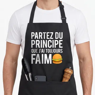 Tablier de cuisine noir avec le texte blanc Partez du principe que j'ai toujours faim et une illustration de burger coloré à côté.