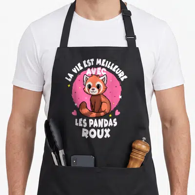 Tablier de cuisine noir avec illustration d'un panda roux souriant sur fond rose et texte blanc.
