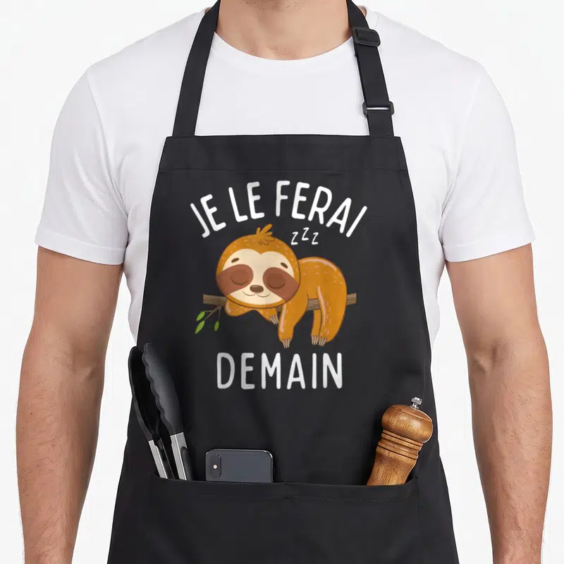 Tablier de cuisine noir avec illustration d'un paresseux dormant et le texte Je le ferai demain en lettres blanches.