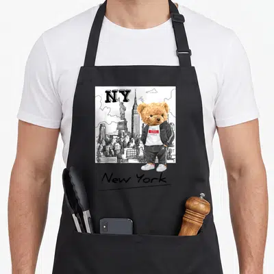Tablier de cuisine noir avec ours en veste noire devant skyline New York et Statue de la Liberté en dessin au trait.