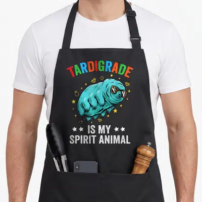Tablier de cuisine noir avec un tardigrade turquoise en lunettes de soleil et des étoiles dorées.
