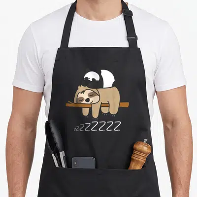Tablier de cuisine noir avec illustration d'un panda et d'un paresseux dormeur sur une branche et le texte zzz.