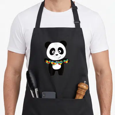 Tablier de cuisine noir avec un panda tenant une guirlande de cœurs en puzzle colorés.