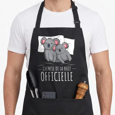 Tablier de cuisine noir avec deux koalas gris blottis sur un oreiller blanc et le texte « chemise de la nuit » imprimé en dessous.