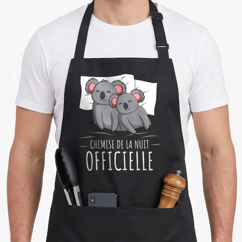 Tablier de cuisine noir avec deux koalas gris blottis sur un oreiller blanc et le texte « chemise de la nuit » imprimé en dessous.