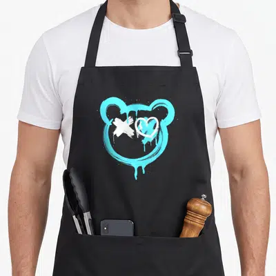 Tablier de cuisine noir avec tête d'ours stylisée en graffiti bleu cyan et motifs blancs sur le visage.