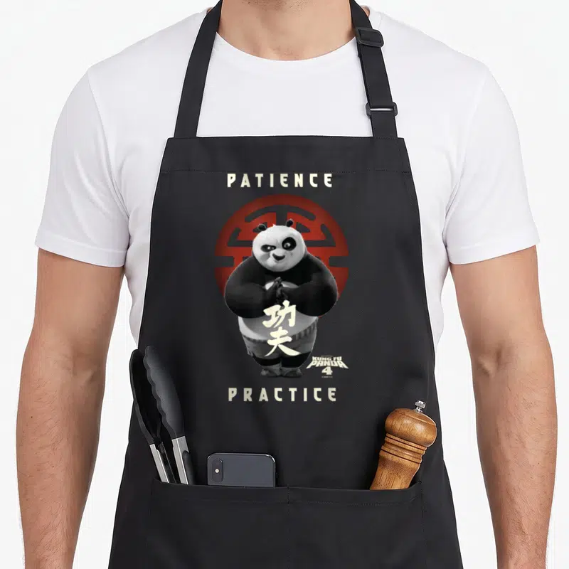 Tablier de cuisine noir avec le portrait du Maître Po, des symboles chinois et les mots Patience Practice en lettres claires sur fond rouge.