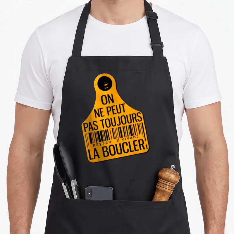 Tablier de cuisine noir avec une étiquette orange portant le texte on ne peut pas toujours la boucler et un code-barres.
