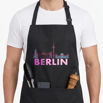 Tablier de cuisine noir avec un skyline de Berlin en mosaïque multicolore et le mot BERLIN en rose