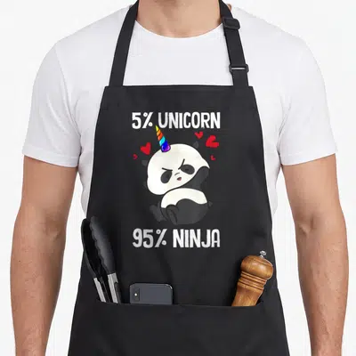 Tablier de cuisine noir avec illustration d'un panda cornu aux yeux fermés entouré de cœurs rouges et de texte blanc.