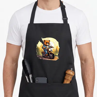 Tablier de cuisine noir avec ours grizzly en veste bleue conduisant une moto orange sur fond de forêt
