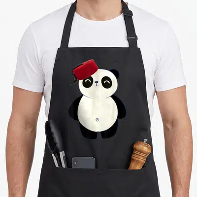 Tablier de cuisine noir avec un panda souriant coiffé d'une chachia rouge à frange noire.
