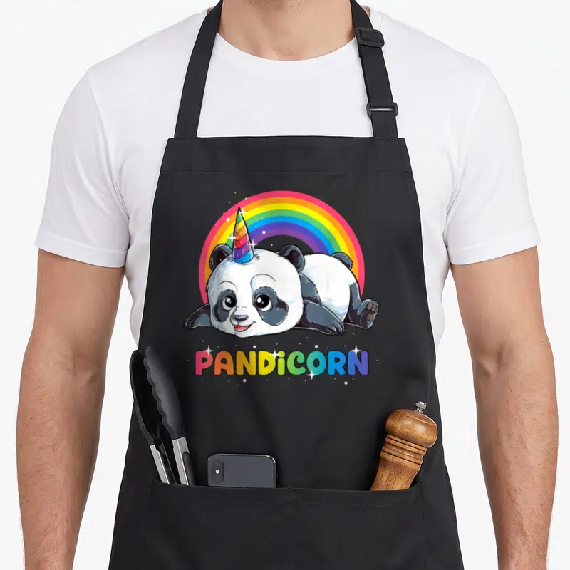 Tablier de cuisine noir avec un panda licorne aux couleurs vives et un arc-en-ciel en arrière-plan.