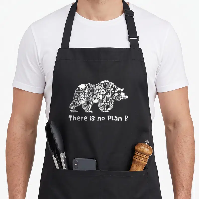 Tablier de cuisine noir avec silhouette d'ours composée d'icônes environnementales et texte blanc en dessous.