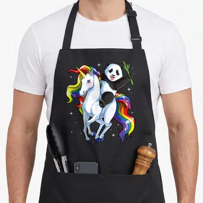Tablier de cuisine noir avec un panda montant une licorne aux cheveux arc-en-ciel tenant une tige de bambou.