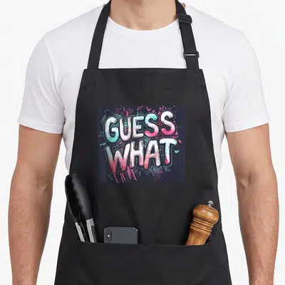 Tablier de cuisine noir avec l'inscription Guess What en lettrage graffiti rose et bleu turquoise.