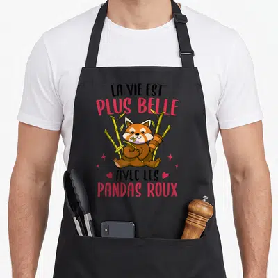 Tablier de cuisine noir avec un panda roux assis dans le bambou et le texte la vie est plus belle avec les pandas roux