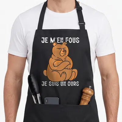 Tablier de cuisine noir avec illustration d'un ours brun assis et texte blanc humoristique.