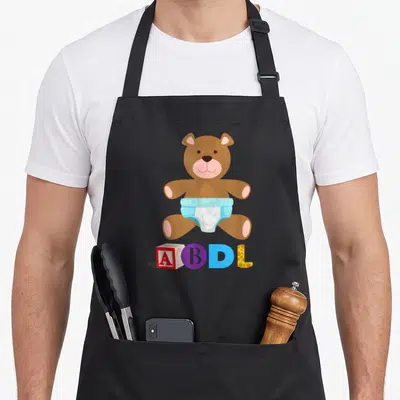 Tablier de cuisine noir avec ours en peluche en diaper et les lettres ABDL colorées.