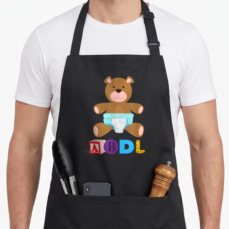 Tablier de cuisine noir avec ours en peluche en diaper et les lettres ABDL colorées.