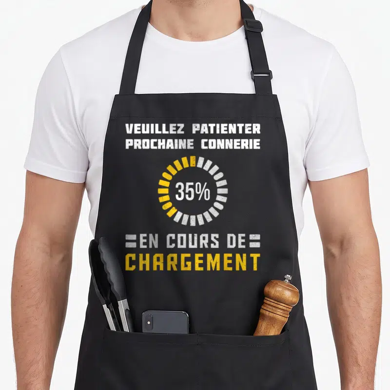 Tablier de cuisine noir avec texte blanc et jaune « Veuillez Patienter Prochaine Connerie En Cours De Chargement » et icône de chargement circulaire.