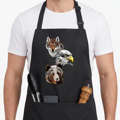 Tablier de cuisine noir avec illustration de têtes d'aigle, loup et ours en style dessin au trait.