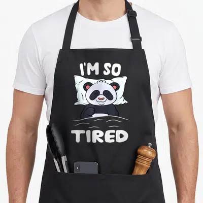 Tablier de cuisine noir avec un panda endormi sur l'oreiller et le texte I'm So Tired en blanc.