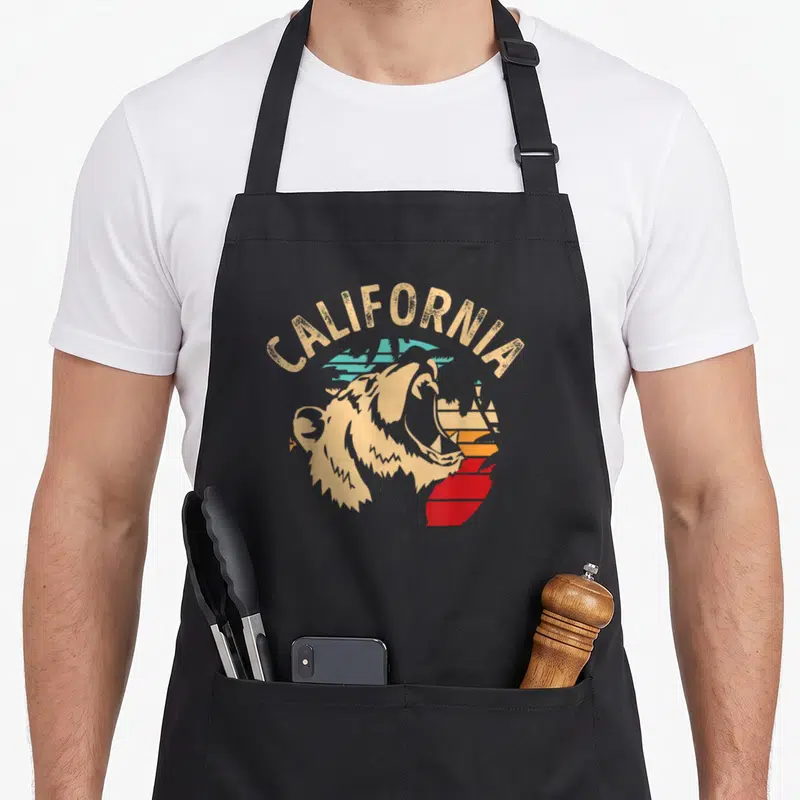 Tablier de cuisine noir avec illustration rétro d'un ours californien et le mot CALIFORNIA en arc au-dessus.
