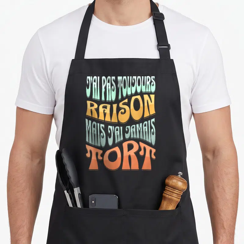 Tablier de cuisine noir avec une inscription humoristique en lettres colorées style vintage sur le devant.