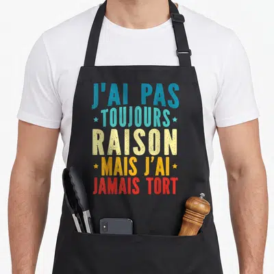 Tablier de cuisine noir avec inscription colorée J'ai pas toujours raison mais j'ai jamais tort et petites étoiles décoratives.