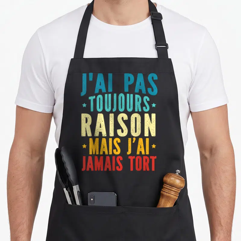 Tablier de cuisine noir avec inscription colorée J'ai pas toujours raison mais j'ai jamais tort et petites étoiles décoratives.