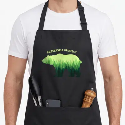 Tablier de cuisine noir avec un ours composé d'arbres verts et le texte Preserve & Protect au-dessus.